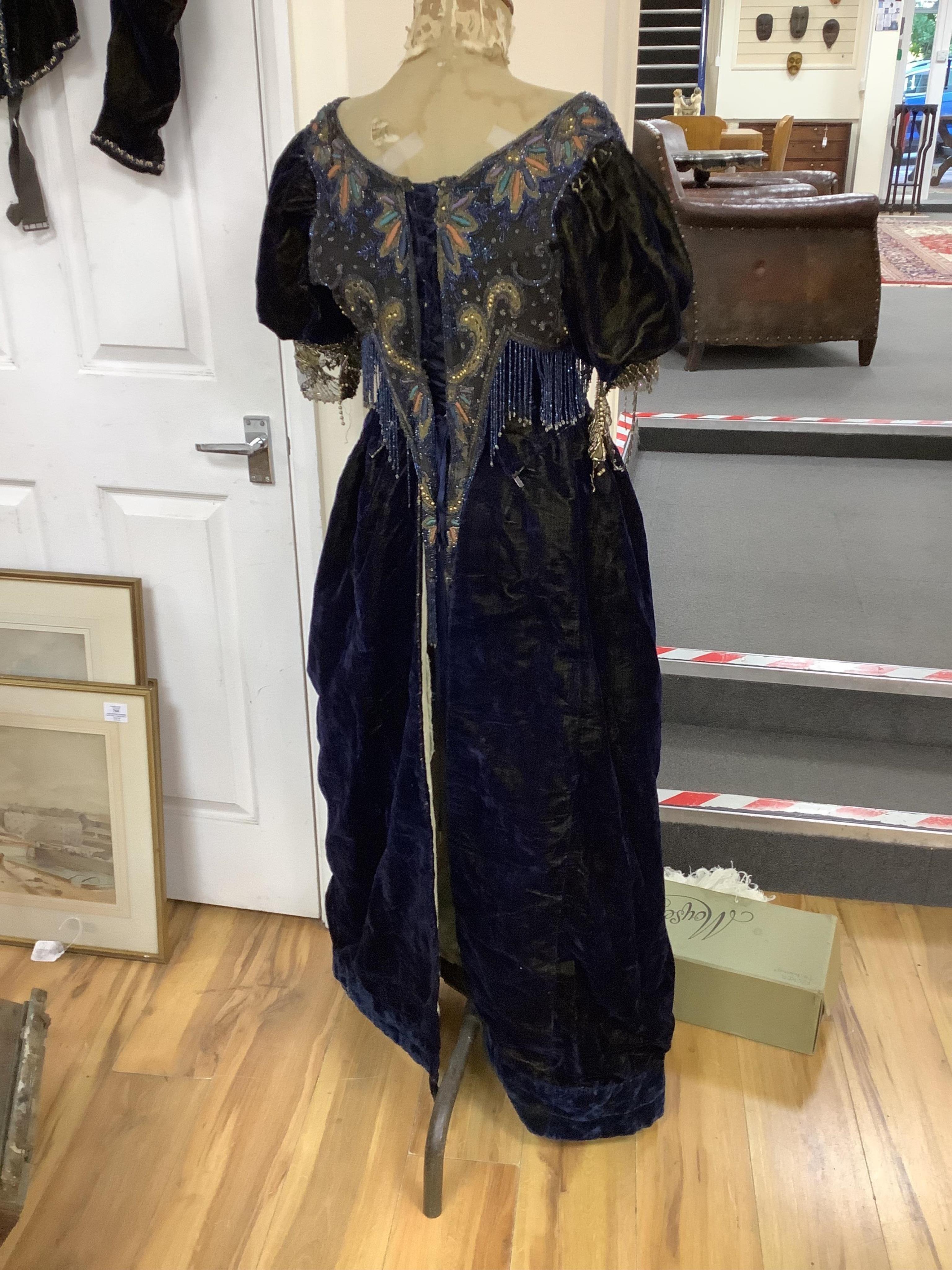 A 19th century ladies silk velvet matching long sleeved jacket/bodice, and skirt, together with another matching short sleeved bead worked bodice and white feather headdress.(4). Cape 106cm long. Condition - Both bodices